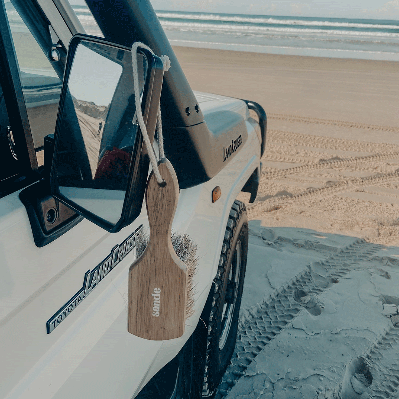 Wooden sand brush hanging from a vehicle&