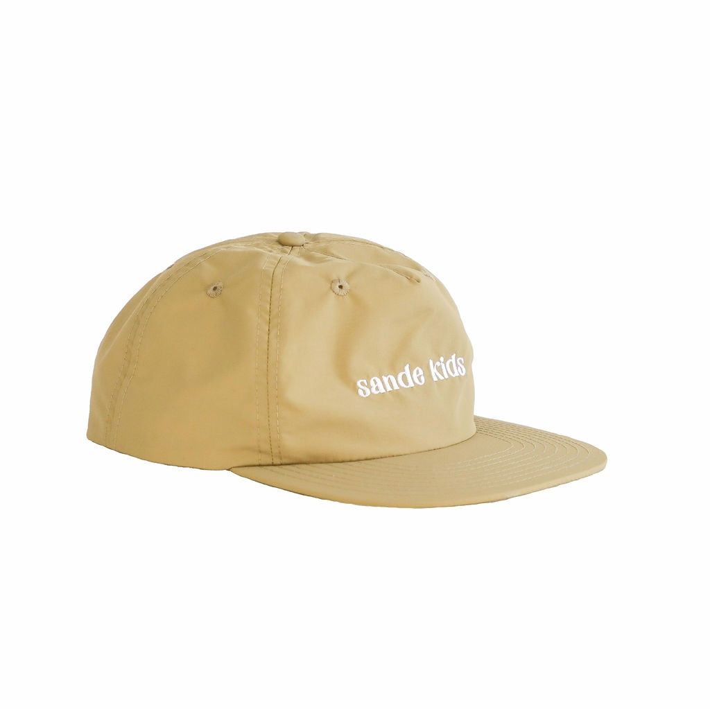 A beige cap made from waterproof nylon fabric, shown from the side. The cap features the Sande Kids™ logo embroidered in white on the front.