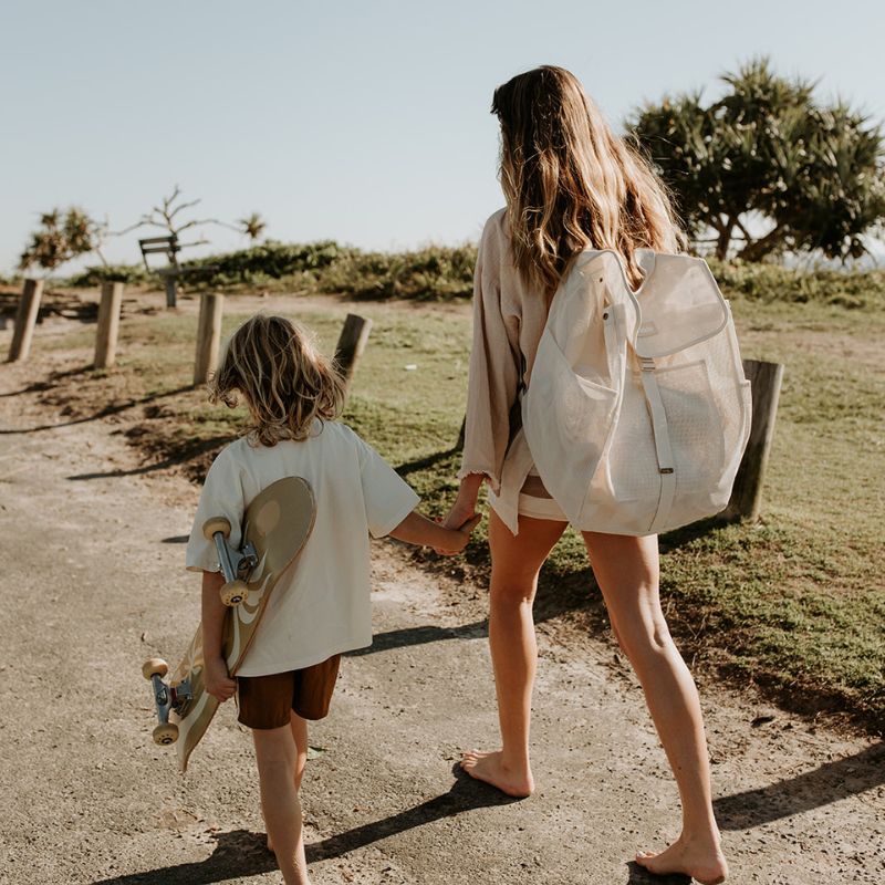 Mum and son walking to the beach, with mum carrying her Sande Kids Beach Hauler mesh beach backpack in neutral Sand colour.