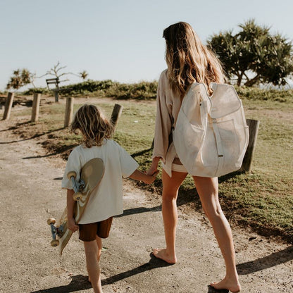 Mum and son walking to the beach, with mum carrying her Sande Kids Beach Hauler mesh beach backpack in neutral Sand colour.