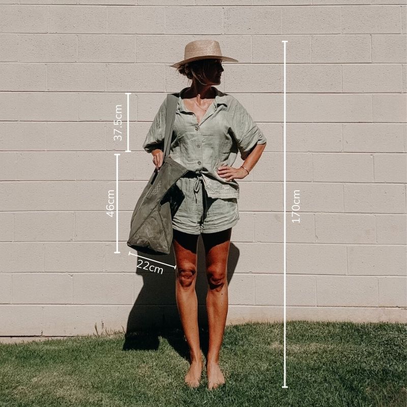 Model 170cm tall holding a Sande Kids Beach Hauler Mini mesh beach bag in a pandanus green.