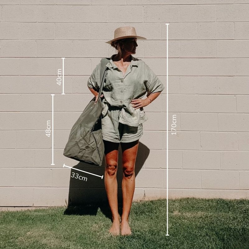 Model 170cm tall demonstrating how the oversized Beach Hauler mesh beach bag in Pandanus green is carried.