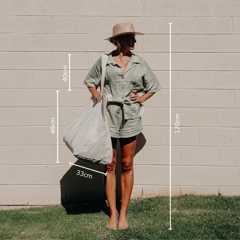 Woman 170cm tall, demonstrating how the Sande Kids Beach Hauler oversized mesh beach bag is carried.