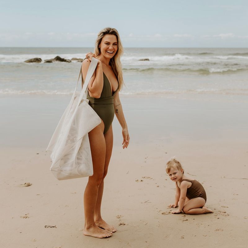 Mother and daughter enjoying a beach day with their oversized Sande Kids Beach Hauler mesh beach bag in neutral Sand, highlighting its spacious and stylish design, perfect for carrying beach essentials and family outings.