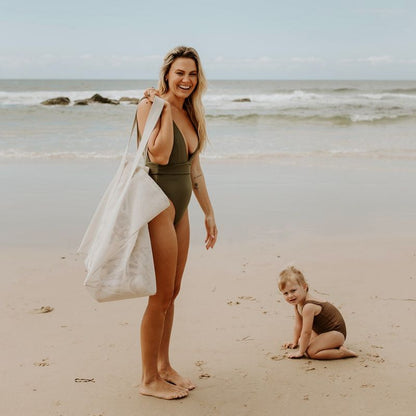 Mother and daughter enjoying a beach day with their oversized Sande Kids Beach Hauler mesh beach bag in neutral Sand, highlighting its spacious and stylish design, perfect for carrying beach essentials and family outings.