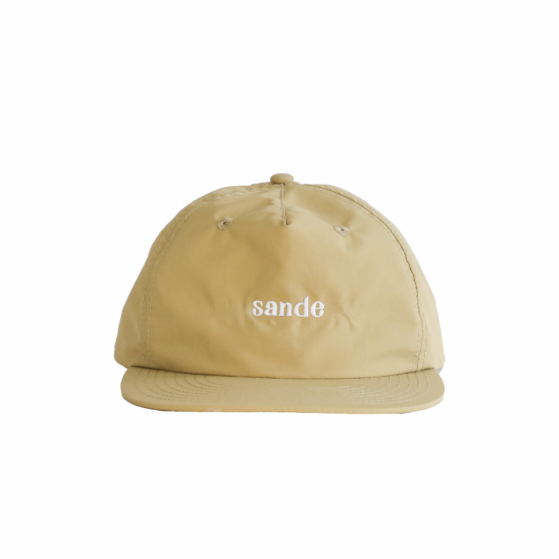 A beige cap made from waterproof nylon fabric, shown from the front. The cap features the Sande™ logo embroidered in white on the front.