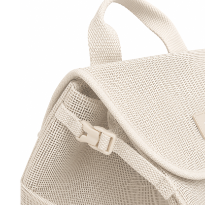 Close up view of the Sande Beach Hauler mesh backpack in neutral Sand, showing the small side clip used to compress the bag.