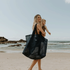 Oversized mesh beach bag, the Sande Beach Hauler in Deep Sea Navy, carried by a mum holding her young daughter at the beach, with the ocean in the background.