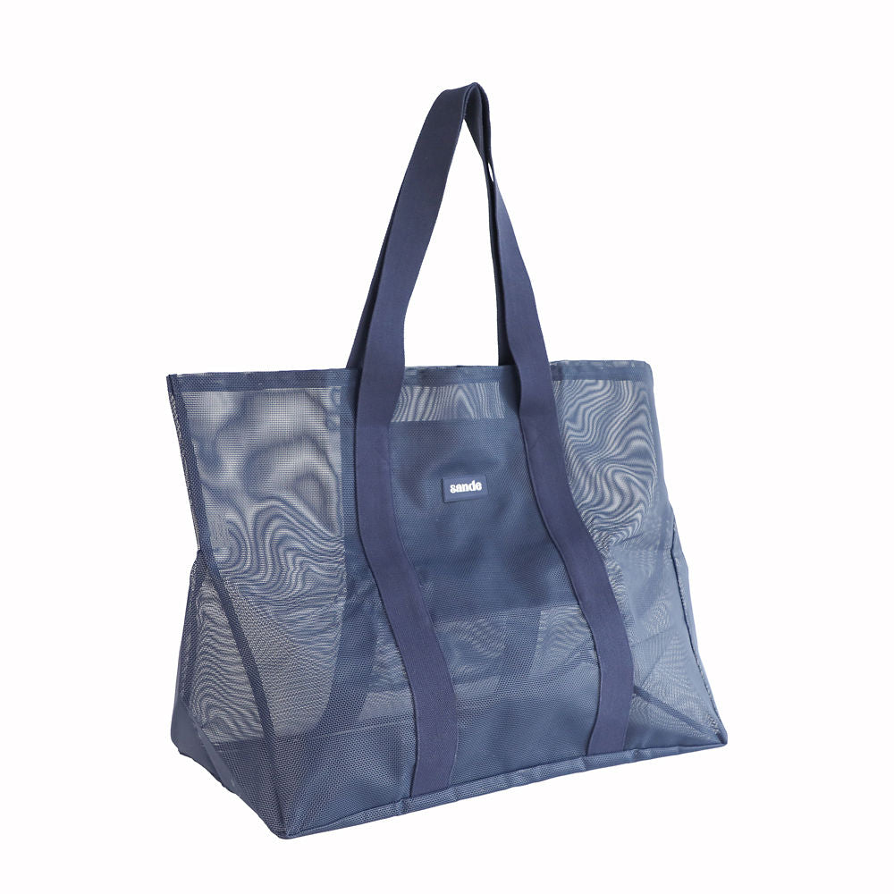 Oversized Sande Beach Hauler mesh beach bag in Deep Sea Navy, displayed in a studio setting. Positioned at a 45° angle to highlight the mesh detail, thick cotton straps, and silicone Sande Kids logo. Set against a white background.
